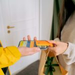 A close-up view of contactless payment transaction using a mobile phone and credit card indoors.