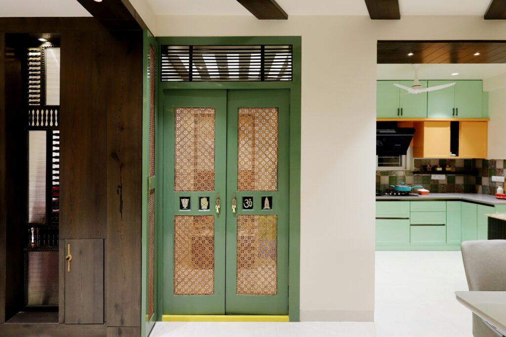 Interior view featuring a stylish Indian home entrance with intricate door designs leading to a modern kitchen.
